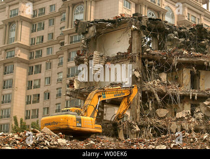 Ein Bulldozer macht schnelle Arbeit der Abriss einer alten Apartment Block, neben einer modernen Wohnanlage, Raum für einen neuen Einkaufs- und Geschäftsviertel zu machen, im Zentrum von Peking, 31. Mai 2006. Während die Olympischen Gebäude-raserei unterwegs ist, sind einige der ältesten Peking Nachbarschaften werden als Teil der Anstrengungen, die die Stadt auf ihrem besten Gesicht von 2008, abgerissen. (UPI Foto/Stephen Rasierer) Stockfoto