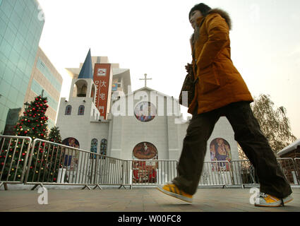 Eine chinesische Frau geht vorbei an einem kleinen Modell Kirche als Teil eines Weihnachten Anzeige vor einem trendigen Büro- und Einkaufszentrum in der Innenstadt von Peking, China, November 04, 2006. Der Vatikan am Samstag sprengte China für Ordination einen anderen Bischof ohne päpstliche Zustimmung für sich, und nannte es die neuesten in einer 'Serie von sehr schwere Handlungen", die Papst Benedikt XVI." großes Leid verursacht." (UPI Foto/Stephen Rasierer) Stockfoto