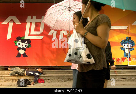 Chinesische Frauen vorbei an einem Obdachlosen vergangen - Vor eine Werbung für die Olympischen Spiele 2008 in Peking in Shenyang, China Am 13. September 2007. (UPI Foto/Stephen Rasierer) Stockfoto