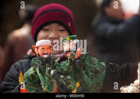 Ein junger chinesischer Junge Boxen mit seiner Mama mit Handpuppen von Osama Bin Laden und Saddam Hussein als vorweihnachtlichen Menschenmassen am ersten Tag des chinesischen neuen Jahres an einem von Pekings wichtigsten kulturellen Parks, voll von Spielzeug und Lebensmittel Lieferanten, am Februar 07, 2008. China Willkommen im Jahr der Ratte Donnerstag mit einer Goldgrube von Feuerwerk und Feste, aber die Feierlichkeiten für viele Waren wegen der grausamen Kälte, die sie von ihren Familien gehalten werden gedämpft. (UPI Foto/Stephen Rasierer) Stockfoto