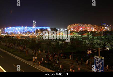 Menschen gehen rund um den Olympischen Grün, mit China's Olympic National Stadium, auch als der Bird's Nest (R) und der Olympische National Aquatic Center, auch als die Watercube bekannte, in der Nacht nur eine Woche vor der Eröffnungsfeier für die Spiele 2008 in Peking, August 01, 2008 bekannt. (UPI Foto/Stephen Rasierer) Stockfoto