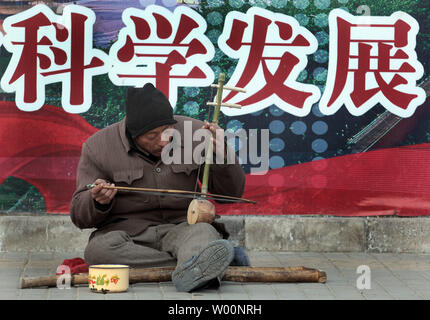 Eine obdachlose Chinesischer Mann spielt eine Erhu, die populärste Streichinstrument in China, während um Geld betteln auf den Straßen der Innenstadt von Beijing am 26. November 2009. Die wirtschaftliche und soziale Reform hat viele in China profitiert, aber die menschlichen Kosten dieser schnelle Wandel hat der Druck auf die Personen und Familien - einer wachsenden Bevölkerung mit Migrationshintergrund, eine höhere Scheidungsrate und eine wachsende Kluft zwischen Arm und Reich. UPI/Stephen Rasierer.. Stockfoto