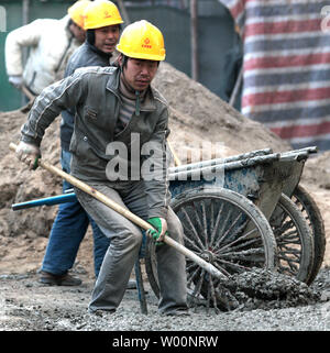 Migrant chinesische Arbeiter schaufel Beton auf einer Baustelle in der Innenstadt von Peking am 26. November 2009. Die wirtschaftliche und soziale Reform hat viele in China profitiert, aber die menschlichen Kosten dieser schnelle Wandel hat der Druck auf die Personen und Familien - einer wachsenden Bevölkerung mit Migrationshintergrund, eine höhere Scheidungsrate und eine wachsende Kluft zwischen Arm und Reich. UPI/Stephen Rasierer.. Stockfoto