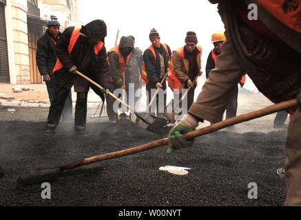 Chinesische Straßenarbeiter Ebene frisch gelegte Asphalt auf einen neuen Parkplatz in Peking am 2. Januar 2010. Chinas Humanressourcen und soziale Sicherheit Minister Yin Weimin warnte vor einer "Grab" Beschäftigungssituation in China, sagte aber staatlichen Maßnahme zur Förderung der Beschäftigung ergriffen' erste Wirkungen". UPI/Stephen Rasierer Stockfoto