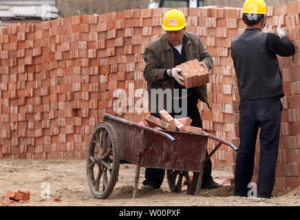 Chinesische Wanderarbeiter haul Backsteine bei einem umstrittenen Baustelle, wo staatlich geschützten Gebäuden durch private Firmen wurden abgerissen, in Peking am 29. April 2010. China letzte Woche versprochen, mit Bauträgern in illegale Praktiken verwickelt. UPI/Stephen Rasierer Stockfoto