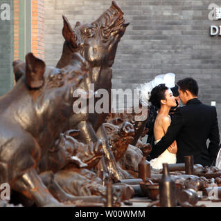 Chinesische Brautpaare posieren für Fotos vor eine Kunstinstallation in Peking, 11. März 2011. Eine zunehmende Bachelor Überschuss in China grenzen Aufwertung des Yuan fast 10 Mal mehr als Maßnahmen der Regierung Beamten beaufsichtigt die zweitgrößte Volkswirtschaft der Welt, nach ein an der Columbia University Economist. UPI/Stephen Rasierer Stockfoto