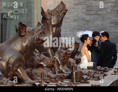 Chinesische Brautpaare posieren für Fotos vor eine Kunstinstallation in Peking, 11. März 2011. Eine zunehmende Bachelor Überschuss in China grenzen Aufwertung des Yuan fast 10 Mal mehr als Maßnahmen der Regierung Beamten beaufsichtigt die zweitgrößte Volkswirtschaft der Welt, nach ein an der Columbia University Economist. UPI/Stephen Rasierer Stockfoto