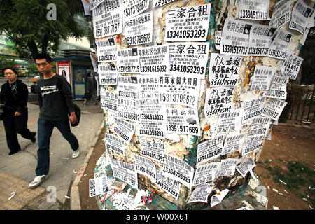 Chinesische Spaziergang, vorbei an der Unterseite eines Lichtmast mit 'Wohnungen für Miete und Verkauf' Aufkleber in Peking am 12. Mai 2011 abgedeckt. Die chinesische Regierung wird ihre Lieferungen von Flächen für den Wohnungsbau Entwicklung in diesem Jahr als Teil der Bemühungen des Landes, seine außer Kontrolle geratenen Immobilienmarkt zu bändigen, nach Angaben des Ministeriums für Land und Ressourcen. UPI/Stephen Rasierer Stockfoto