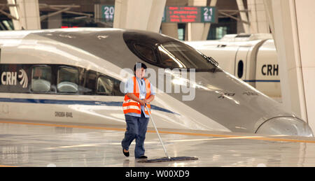 Ein Arbeiter fegt wie CRH High-Speed-Züge ankommen und von Pekings neue, hochmoderne Südbahnhof am 27. Juni 2011 ab. Chinesische Ingenieure leiteten einen Test-run Der beijing-shanghai high-speed Rail Link, Tage vor seiner öffentlichen starten. Beamte, Reporter und Firmenchefs waren an Bord für die 300 km/h (190 mph) Maiden's Train Reise. UPI/Stephen Rasierer Stockfoto