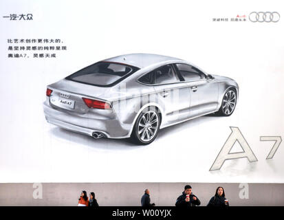 Chinesische Spaziergang, vorbei an einem großen Plakat werbung ein neues Auto auf Verkauf in Peking am 13. Dezember 2011. Die Automobilindustrie in China hat die größte in der Welt wurde von der Produktion Volumen gemessen seit 2008. Einen unverhältnismäßig großen Anteil an der Chinesischen hat immer schwerer Fahrzeuge gewesen, aber seit 2000 Chinas Wachstum wurde durch die Zunahme der Pkw geführt worden. UPI/Stephen Rasierer Stockfoto