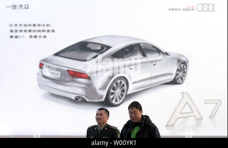 Chinesische Spaziergang, vorbei an einem großen Plakat werbung ein neues Auto auf Verkauf in Peking am 13. Dezember 2011. Die Automobilindustrie in China hat die größte in der Welt wurde von der Produktion Volumen gemessen seit 2008. Einen unverhältnismäßig großen Anteil an der Chinesischen hat immer schwerer Fahrzeuge gewesen, aber seit 2000 Chinas Wachstum wurde durch die Zunahme der Pkw geführt worden. UPI/Stephen Rasierer Stockfoto