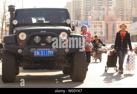 Chinesische Fußgänger vorbei an einen amerikanischen Jeep geparkt Straßenkante in Peking den 16. Dezember 2011. China Strafzölle von bis zu 22 Prozent auf große Autos und SUVs aus den Vereinigten Staaten exportiert auferlegen, Chinas Handel Ministerium sagte in dieser Woche, die letzte in einer Reihe von Handelsstreitigkeiten zwischen den zwei größten Volkswirtschaften der Welt. UPI/Stephen Rasierer Stockfoto