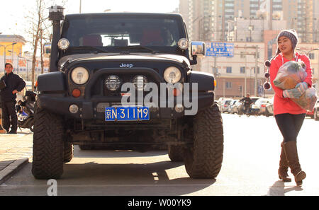 Chinesische Fußgänger vorbei an einen amerikanischen Jeep geparkt Straßenkante in Peking den 16. Dezember 2011. China Strafzölle von bis zu 22 Prozent auf große Autos und SUVs aus den Vereinigten Staaten exportiert auferlegen, Chinas Handel Ministerium sagte in dieser Woche, die letzte in einer Reihe von Handelsstreitigkeiten zwischen den zwei größten Volkswirtschaften der Welt. UPI/Stephen Rasierer Stockfoto