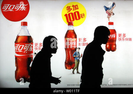 Eine chinesische Spaziergang, vorbei an einer Anschlagtafel Werbung Coca-Cola Erfrischungsgetränke auf den Straßen von Peking am 23. Oktober 2012. Letzte Woche sagte, dass die Verkäufe von Coca-Cola in China eine blutarme 2% im Vergleich zu 11 Prozent im letzten Jahr gestiegen. Aktien des weltweit größten Getränkehersteller verloren in diesem Monat mehr als 2%, vor allem wegen der Verlangsamung der chinesischen Wirtschaft. UPI/Stephen Rasierer Stockfoto