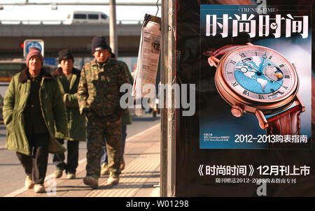 Armen chinesischen Migranten Bauarbeiter vorbei einen News Stand mit einem Magazin für Luxusgüter in Peking am 11. Dezember 2012 zu arbeiten. Milliarden an nicht gemeldeten Einkommen für die Reichen und eine korrupte soziales System, Gesundheit und Rente für Migranten und älteren Menschen ist die chinesische Analysten eine noch größere Einkommensunterschiede als anerkannt. UPI/Stephen Rasierer Stockfoto