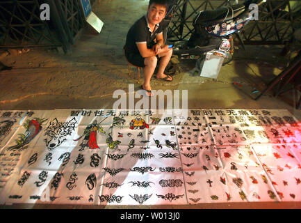 Ein chinesischer Mann verkauft temporäre Tattoos auf einer Straße in Peking am 27. August 2013. Mit der chinesischen Wirtschaft verlangsamt sich, weniger Arbeitsplätze für neue Hochschulabsolventen zur Verfügung stehen und für junge chinesische Versuchen, den Job zu machen. UPI/Stephen Rasierer Stockfoto