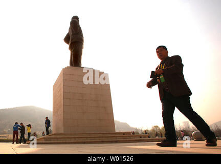 Chinesische vorbei durch eine große Statue von Chinas ehemaligen Steuermann Mao Zedong bei der Ankunft im Revolutionären Memorial Hall, präsentiert die Ereignisse, die zu der Entstehung der Volksrepublik China führte, in Yan'an, Provinz Shaanxi, am 6. April 2014. Yan'an war in der Nähe der Endpunkt der Langen Marsch, und wurde zum Zentrum der Chinesischen Kommunistischen Revolution führte meine Mao von 1936 bis 1948. Die chinesischen Kommunisten feiern die Stadt als Geburtsstätte des modernen China und der Kult von Mao. UPI/Stephen Rasierer Stockfoto