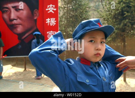 Ein chinesischer Junge gekleidet in eine kommunistische Uniform für ein Foto bereitet, vor einem Banner der ideale Soldat Li Feng der kommunistischen Partei, die an einem Standort durch ehemalige Steuermann Mao Zedong und anderen Führern verwendet Politik und zukünftige Strategien in der Yangjialing Revolution zu diskutieren, in Yan'an, Provinz Shaanxi, am 6. April 2014. Yan'an war in der Nähe der Endpunkt der Langen Marsch, und wurde zum Zentrum der Chinesischen Kommunistischen Revolution führte meine Mao von 1936 bis 1948. Die chinesischen Kommunisten feiern die Stadt als Geburtsstätte des modernen China und der Kult von Mao. UPI/Stephen Rasierer Stockfoto