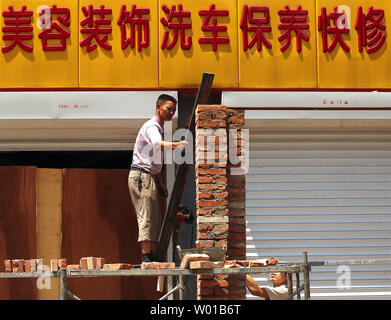 Ein chinesischer Arbeiter baut eine Mauer zwischen zwei Garagen im Zentrum von Peking am 27. Juni 2016. Turbulenzen unleashed von dem Britischen Abstimmung auf die Europäische Union (EU) verlassen erhöhte Ängste in Asien mit China, Japan und Südkorea alle über das finanzielle Risiko für ihre Volkswirtschaften alarmiert. Chinas Finanzminister sagte Fallout aus der vergangenen Woche Referendum" wird ein Schatten über der globalen Wirtschaft" werfen. Foto von Stephen Rasierer/UPI Stockfoto