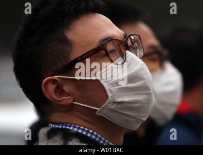 Chinesische tragen Gesichtsmasken gegen die schweren Smog über Peking am 17. November 2016 zu schützen. Die Hauptstadt Chinas warnte seine 20 Millionen Einwohner outdoor Aktivitäten zur Begrenzung der negativen Auswirkungen der starke Verschmutzung die Stadt zu vermeiden. Foto von Stephen Rasierer/UPI Stockfoto