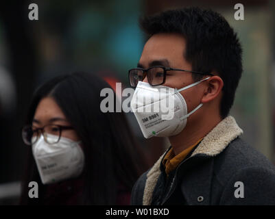 Chinesische tragen Gesichtsmasken gegen die schweren Smog über Peking am 17. November 2016 zu schützen. Die Hauptstadt Chinas warnte seine 20 Millionen Einwohner outdoor Aktivitäten zur Begrenzung der negativen Auswirkungen der starke Verschmutzung die Stadt zu vermeiden. Foto von Stephen Rasierer/UPI Stockfoto