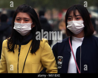 Chinesische tragen Gesichtsmasken gegen die schweren Smog über Peking am 17. November 2016 zu schützen. Die Hauptstadt Chinas warnte seine 20 Millionen Einwohner outdoor Aktivitäten zur Begrenzung der negativen Auswirkungen der starke Verschmutzung die Stadt zu vermeiden. Foto von Stephen Rasierer/UPI Stockfoto