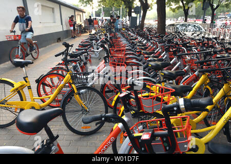 Ein chinesischer Mann reitet letzten Zeilen von mobike (orange) und Ofo bike Bikes auf einem Bürgersteig in Peking am 17. Juli 2017. Bike giant Mobike, die sagen, es hat nicht weniger als 25 Millionen Reiter ein Tag in China, ist angeblich auf der Suche Mitfahrer auf ihre Fahrräder in der US-Hauptstadt zu setzen und mit der Rekrutierung des Operation Manager gestartet. Foto von Stephen Rasierer/UPI Stockfoto