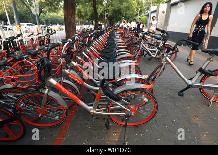 Eine chinesische Frau geht letzten Zeilen von Mobike bike Bikes auf einem Bürgersteig in Peking am 17. Juli 2017. Bike giant Mobike, die sagen, es hat nicht weniger als 25 Millionen Reiter ein Tag in China, ist angeblich auf der Suche Mitfahrer auf ihre Fahrräder in der US-Hauptstadt zu setzen und mit der Rekrutierung des Operation Manager gestartet. Foto von Stephen Rasierer/UPI Stockfoto