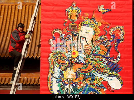 Ein chinesischer Arbeiter legt den letzten Schliff für das Aufhängen von großen Tempel Gottes Wandmalereien auf der Vorderseite Tor von einem Tempel in Peking am 29. Januar 2018. Chinas Hauptstadt rüstet sich für die anstehende Chinesisches Neujahr und Spring Festival, das wird das Jahr des Hundes sein. Foto von Stephen Rasierer/UPI Stockfoto