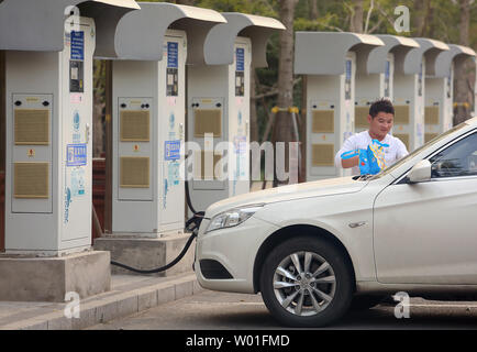 Ein chinesischer Mann wartet auf seine chinesischen elektronische Fahrzeug (EV) - in einem der vielen Ladestationen in Peking am 14. Oktober 2018 mit Strom versorgt werden. China ist der größte Automobilmarkt der Welt, und seine Regierung hat der Welt größter Verfechter der elektrischen Autos geworden. China entfallen 40 Prozent aller elektrischen Autos weltweit verkauft. Foto von Stephen Rasierer/UPI Stockfoto