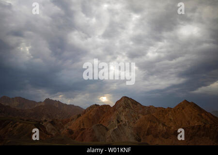 An einem bewölkten Tag, Danxia, ein Strahl der Sonne durch die dunklen Wolken. Stockfoto