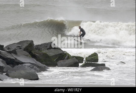 Ein einsamer Surfer reitet den rauhen Wellen in der Nähe der Felsen am Strand in Atlantic City, New Jersey nach Hurrikan Irene der Bereich am 28. August 2011. Die Kategorie eine Geschichte hat die Jersey Shore nicht Schaden so viel wie erwartet, aber massive Überflutungen erwartet wird. UPI/John Anderson Stockfoto