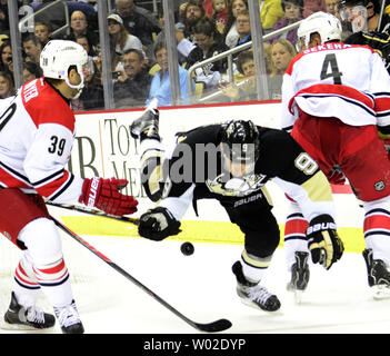 Pittsburgh Penguins rechten Flügel Pascal Dupuis (9) Fällt auf dem Eis, als er den Puck zwischen Carolina Hurricanes rechten Flügel Patrick Dwyer (39) und Carolina Hurricanes defenseman Andrej Sekera (4) in der zweiten Periode am Consol Energy Center in Pittsburgh am 8. Oktober 2013. UPI/Archie Tischler Stockfoto