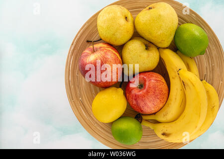 Früchte auf einem Teller. Äpfel, Birnen, Bananen, Zitronen und Limetten. Ansicht von oben, Kopieren Raum Stockfoto