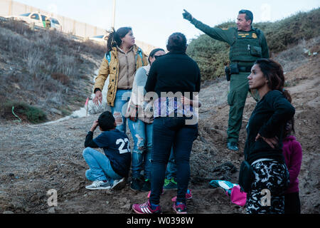 Ein US Border Patrol-Agent spricht mit den Frauen und Kindern, die illegal in San Ysidro, Kalifornien überquert, am 2. Dezember 2018. Mit wachsender Frustration an die Dauer der Asylverfahren, ein Dutzend Migranten entscheiden, den Grenzzaun, teilt den Vereinigten Staaten und Mexiko zu springen. Foto von Ariana Drehsler/UPI Stockfoto