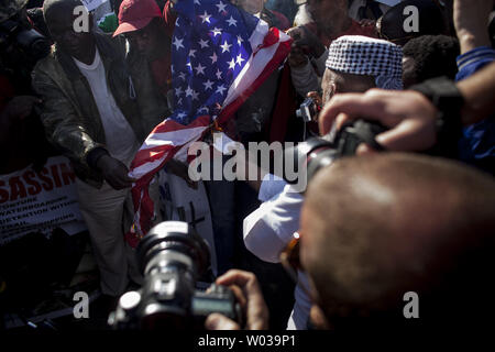 Eine amerikanische Flagge wird auf dem Parkplatz der US-Botschaft als großes Protestgruppe Kundgebungen in Pretoria, South Arfica, aus Protest gegen den Besuch des US-Präsidenten Barack Obama in Südafrika am 28. Juni 2013 verbrannt. Us-Präsident Barack Obama fliegt in Südafrika heute zu einem dreitägigen Besuch während der ehemalige südafrikanische Präsident Nelson Mandela verbringt seine 21. Tag in kritischem Zustand in der Mediclinic Heart Hospital in Pretoria hospitalisiert. UPI/Charlie Schuster Stockfoto