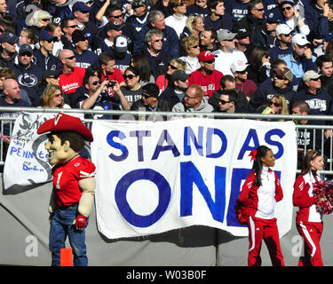 Eine Nebraska Cheerleader und Maskottchen stehen vor der Zeichen von Student an Beaver Stadium in State College, Pennsylvania gebildet am 12. November 2011. Nebraska ist 17-14 gewinnen Sie eine Woche verschlossen, dass die Entlassung von Head Coach Joe Paterno und andere Führer sah an der Penn State University Nach der Festnahme des ehemaligen Assistant Coach Jerry Sandusky über mutmaßliche Fälle von Kindesmissbrauch. UPI/Archie Tischler Stockfoto