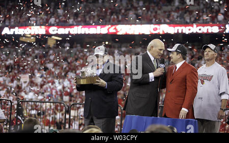 Arizona Cardinals Inhaber Bill Bidwill (L) hält die George Halas Trophäe als Kommentator Terry Bradshaw (zweiter von links) Interviews team Präsident Michael Bidwill (dritter von links) als Coach Ken Whisenhunt (R) auf nach dem Sieg über die Philadelphia Eagles im NFC Championship Game an der Universität von Phoenix Stadium in Glendale, Arizona, 18. Januar 2009 sieht. Die Kardinäle gewann 32-25. (UPI Foto/Paul Connors) Stockfoto