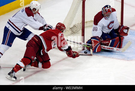 Matt Carolina Hurricanes' Cullen, Mitte und Montreal Canadiens" Michael Komisarek, Links, erreichen für den Kobold als Canadiens goalie Cristobal Huet blockiert die net in der dritten Periode, während Spiel 2 der NHL Eastern Conference Viertelfinale im RBC Center in Raleigh, NC 24. April 2006. Montreal gewann in der zweiten Überstunden, 6-5. (UPI Foto/Jeffrey A. Camarati) Stockfoto