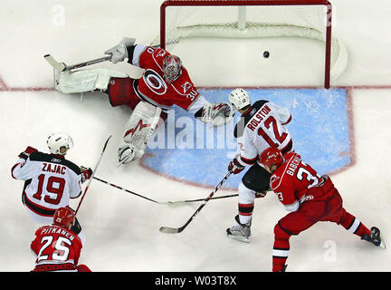 New Jersey Devils' Travis Zajac (19) schießt den Puck Vergangenheit Cam Carolina Hurricanes' Ward (30) Teufel' von Brian Rolston Anton (12) Hurrikane "Babchuk (33) und Hurrikane "Joni Pitkanen (25) in der Nähe das Spiel während der Überstunden der NHL Eastern Conference Viertelfinale Eishockey Spiel in Raleigh, North Carolina, 19. April 2009 zu gewinnen. Teufel gewannen 3-2 in überstunden und die Reihe 2-1 führen. (UPI Foto/Karl DeBlaker) Stockfoto