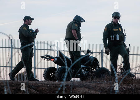 Us Border Patrol-Agenten watch illegals in San Ysidro, Kalifornien am Dezember 2, 2018. Mit wachsender Frustration an die Dauer der Asylverfahren, ein Dutzend Migranten entscheiden, den Grenzzaun, teilt den Vereinigten Staaten und Mexiko zu springen. Foto von Ariana Drehsler/UPI Stockfoto