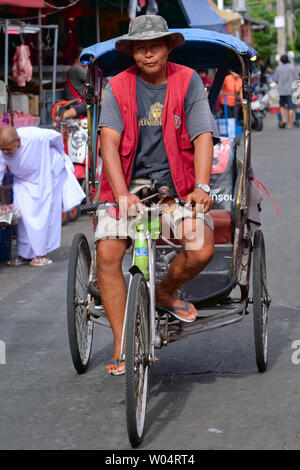 Ein Fahrer mit einem der wenigen verbliebenen samlor oder dreirädrige Zyklus Rikschas in Thailand, auf einem Markt in Pamukkale in der Nähe von Bangkok Stockfoto