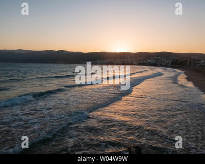 Spritzer schäumenden Wellen des Meeres Beat am Kiesstrand in den Strahlen der untergehenden Sonne. Tasucu, Silifke, Provinz Mersin, Türkei. Stockfoto