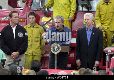 Us-Präsident George W. Bush spricht zu Feuerwehrmänner von der Rückseite der Pickup Truck bei einem Besuch der Brand Camp in Gillespie Flugplatz in El Cajon, Kalifornien, November 4, 2003. Bush traf sich mit Feuerwehrmänner, die die Flammen, die sich über mehr als 743,000 Hektar fegte gekämpft, getötet 22, und tausend Menschen obdachlos. Der Präsident Befragten auch die Region mit dem Hubschrauber und Fuß mit Kalifornien reg. Gray Davis (R) und Regler - wählen Sie Arnold Schwarzenegger (L) (UPI/EARL S. CRYER) Stockfoto