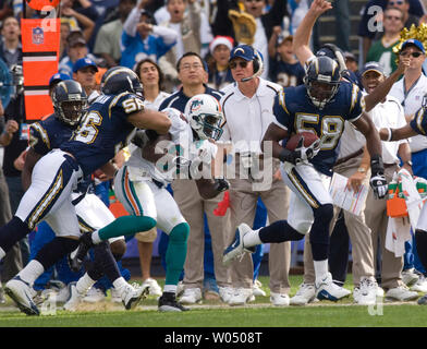 San Diego Chargers linebacker Shawne Merriman (L), sendet der Miami Dolphins Empfänger Chris Chambers flying out of bounds während Ladegerät linebacker Randall Godfrey, 58, auf einem Fumble return im zweiten Quartal läuft, 11. Dezember 2005, in dem Qualcomm Stadium in San Diego. Ladegeräte Head Coach Marty Schottenheimer (C) an schaut. (UPI Foto/Joel Zwink) Stockfoto