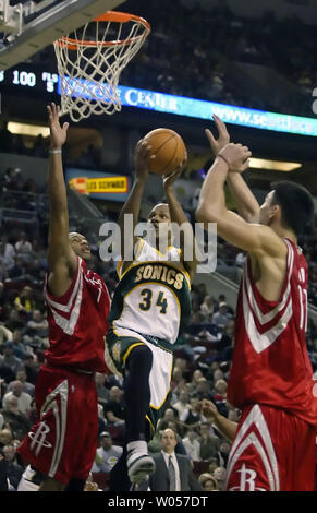 Seattle Supersonics" Ray Allen, Zentrum Splits Houston Rockets Verteidiger Tracy McGrady, Links, und Yao Ming, China, rechts, während er für ein layup im vierten Quartal in der Key Arena in Seattle am 15. Dezember 2005. Allen zählte 30 Punkte in der Supersonics 98-104 Verlust zu den Raketen. (UPI Foto/Jim Bryant) Stockfoto