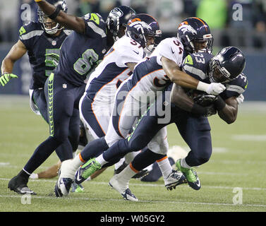 Seattle Seahawks zurück läuft, Christine Michael (33) wird nach Denver Broncos Lorenxo Doss (37) und Ross Madison (34) während des Quartals an CenturyLink Feld brachte am 14. August 2015 in Seattle, Washington. Die Broncos schlagen die Seahawks 22-20. Foto von Jim Bryant/UPI Stockfoto