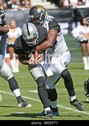 Oakland Raiders QB Terrelle Pryor ist sacked durch Jacksonville Jaguars Jeremy Mincey (94) für ein 7 Yard Verlust im dritten Quartal an O. co Coliseum in Oakland, Kalifornien am 15. September 2013. Die Räuber besiegt die Jaguare, 19-9. UPI/Bruce Gordon Stockfoto