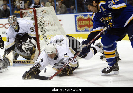 St. Louis Blues Scott Mellanby(R) versucht seinen Stock auf den Puck wie Pittsburgh Penguins Marc Bergevin (25) die Tauchgänge am Puck, während Torhüter Sebastien Caron auf in der ersten Periode am Savvis Center in St. Louis am 14. Februar 2004 sieht zu erhalten. (UPI Foto/Rechnung Greenblatt) Stockfoto