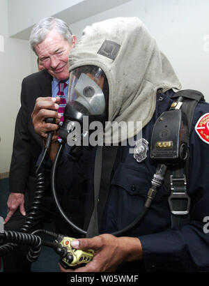 Senator Christopher 'Kit' Bond (R-Mo) Uhren als St. Louis fire fighter Alex Houge macht einen Testanruf im Radio beim Tragen seiner Umluftunabhängiges Atemschutzgerät, nach der Ankündigung, dass Bond fast $ 400 Tausend in der Bundesfinanzierung für die Abteilung neue Ausrüstung zu kaufen gesichert hatte, an der St. Louis Feuerwehr Hauptquartier in St. Louis am 8. März 2004. Einige der Geräte mit der Grant gekauft werden, Maske montiert werden Voice Verstärker, die Kommunikation einfacher, wenn die Feuerwehrleute ihr Gesicht Stücke auf. (UPI Foto/Rechnung Greenblatt) Stockfoto